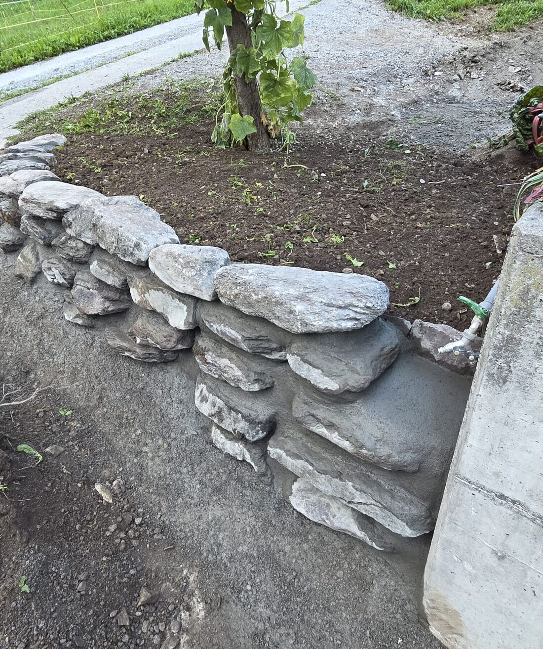 Natursteinmauer um ein Gartenbeet, trocken gesetzt